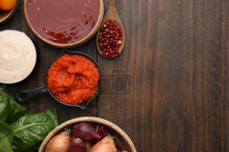 Different marinades and products on wooden table, flat lay. Space for text