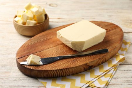 Tasty butter and knife on light wooden table