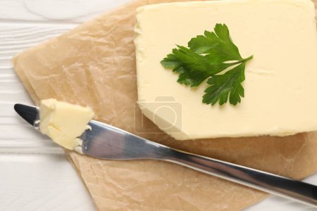 Tasty butter and knife on white wooden table, top view