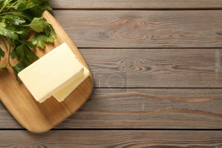 Tasty butter and parsley on wooden table, top view. Space for text