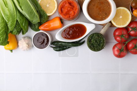 Different marinades and products on white tiled table, flat lay. Space for text