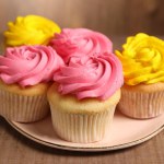 Delicious cupcakes with bright cream on wooden table, closeup