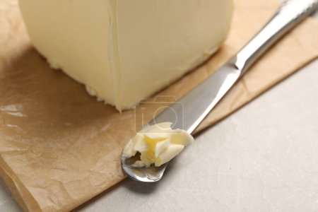 Block von leckerer Butter und Messer auf hellem Tisch, Nahaufnahme