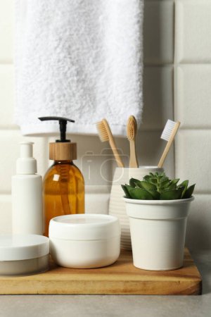 Téléchargez les photos : Différents accessoires de bain et produits de soins personnels sur table grise près du mur carrelé blanc - en image libre de droit