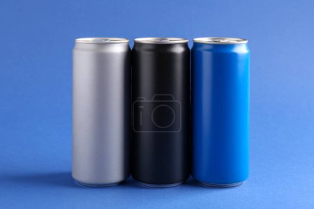 Foto de Bebidas energéticas en latas de colores sobre fondo azul - Imagen libre de derechos