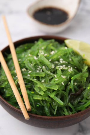 Téléchargez les photos : Salade d'algues savoureuse dans un bol servi sur une table blanche, gros plan - en image libre de droit