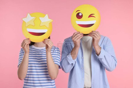 Foto de Personas cubriendo caras con emoticonos sobre fondo rosa - Imagen libre de derechos