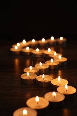 Téléchargez les photos : Brûler des bougies sur une table en bois dans l'obscurité - en image libre de droit