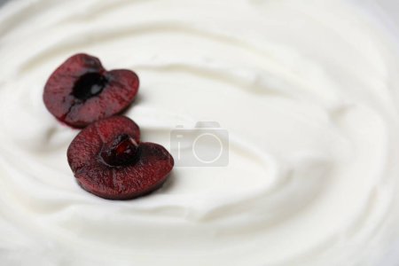 Sabroso yogur con cereza cortada como fondo, primer plano. Espacio para texto