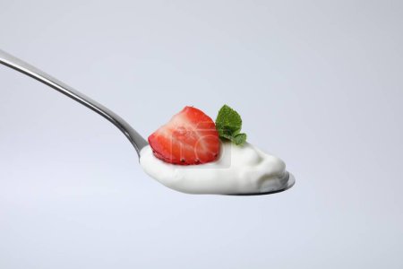 Cuchara con yogur, fresa y menta aislada en blanco