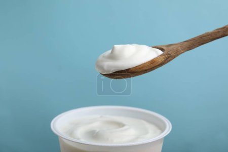 Comer delicioso yogur natural sobre fondo azul claro