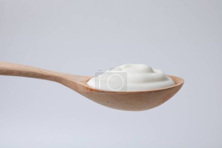 Delicioso yogur natural en cuchara sobre fondo claro