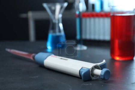 Photo for Laboratory analysis. Micropipette with liquid on black table, closeup - Royalty Free Image