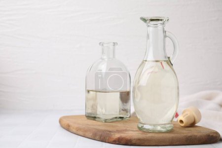 Foto de Vinagre en jarra de vidrio y botella sobre mesa blanca, espacio para texto - Imagen libre de derechos