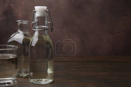 Foto de Vinagre en botellas y vidrio sobre mesa de madera, espacio para texto - Imagen libre de derechos