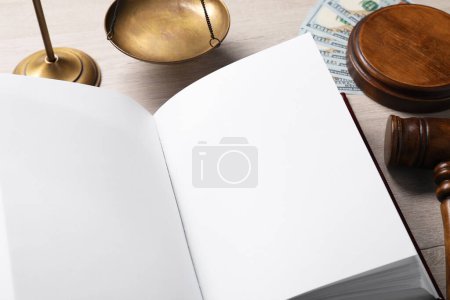 Foto de Derecho fiscal. Libro abierto, martillo, billetes de dólar y escamas en la mesa de madera, primer plano - Imagen libre de derechos