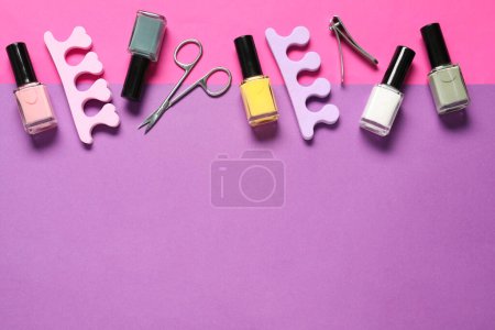 Nail polishes, clippers, scissors and toe separators on color background, flat lay. Space for text