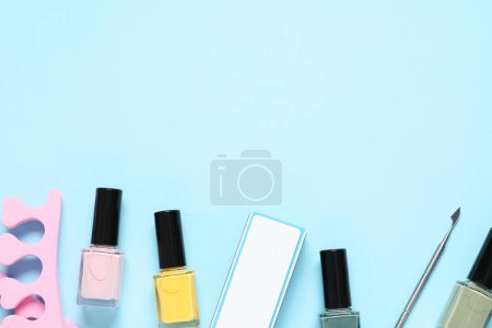 Foto de Esmaltes de uñas, separadores de dedos, amortiguador y empujador de cutículas sobre fondo azul claro, posición plana. Espacio para texto - Imagen libre de derechos