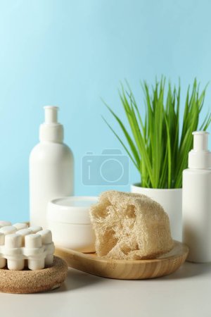 Téléchargez les photos : Différents accessoires de bain et plante d'intérieur sur table blanche sur fond bleu clair - en image libre de droit
