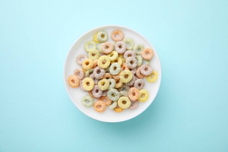 Photo for Tasty colorful cereal rings and milk in bowl on turquoise background, top view - Royalty Free Image