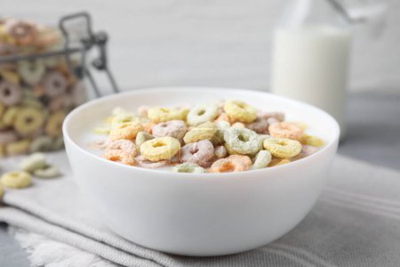 Photo for Tasty colorful cereal rings and milk in bowl on table, closeup - Royalty Free Image