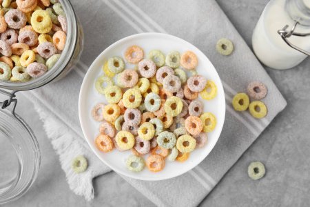 Photo for Tasty colorful cereal rings and milk in bowl on grey table, flat lay - Royalty Free Image