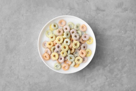 Photo for Tasty colorful cereal rings and milk in bowl on grey table, top view - Royalty Free Image