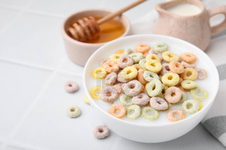 Photo for Cereal rings and milk in bowl on white tiled table, closeup. Space for text - Royalty Free Image