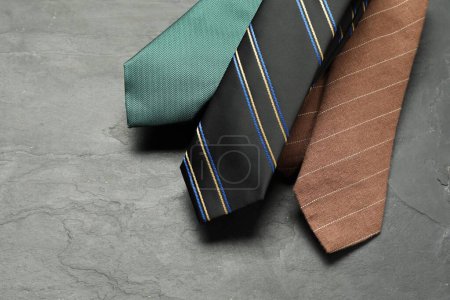 Different neckties on grey textured background, above view. Space for text