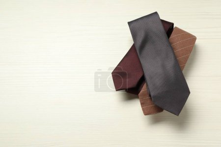 Different neckties on white wooden table, top view. Space for text