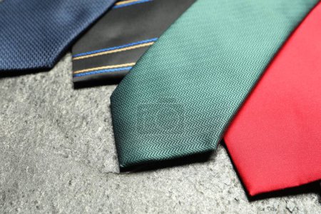 Different neckties on grey textured background, closeup
