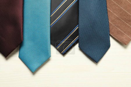 Different neckties on white wooden table, flat lay