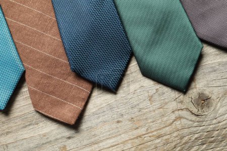 Different neckties on light wooden table, flat lay