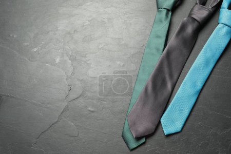 Different neckties on grey textured table, flat lay. Space for text