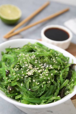 Tasty seaweed salad in bowl served on gray table, closeup