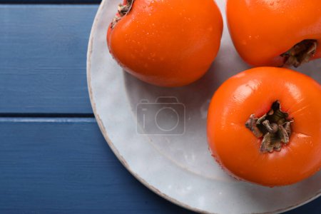 Foto de Deliciosos caquis maduros sobre mesa de madera azul, vista superior. Espacio para texto - Imagen libre de derechos