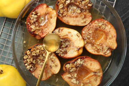 Tasty baked quinces with walnuts and honey in bowl on table, flat lay