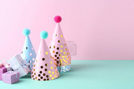 Photo for Party hats and gift boxes on color background, space for text - Royalty Free Image