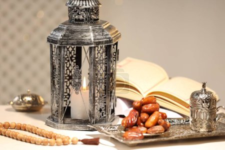 Arabic lantern, Quran, misbaha and dates on white table