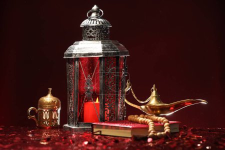 Arabic lantern, Quran, misbaha and Aladdin magic lamp on shiny red table