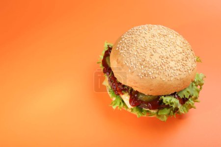 Delicious cheeseburger on coral background, above view. Space for text