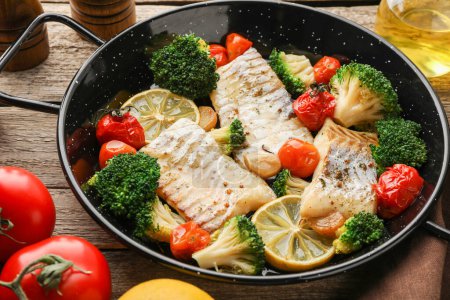 Foto de Sabroso bacalao cocido con verduras en sartén sobre mesa de madera - Imagen libre de derechos