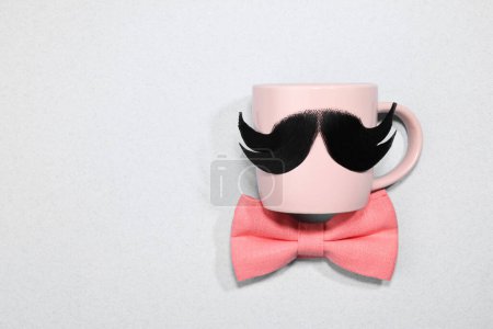 Téléchargez les photos : Visage d'homme fait de moustache artificielle, noeud papillon et lunettes sur fond gris clair, vue de dessus. Espace pour le texte - en image libre de droit