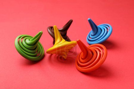 Many colorful spinning tops on red background, closeup