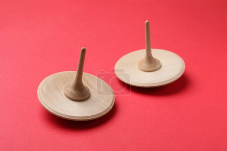 Two wooden spinning tops on red background, closeup