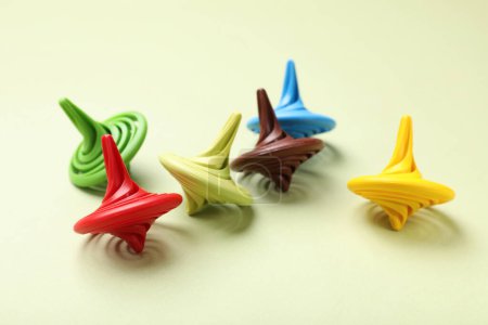 Many colorful spinning tops on green background, closeup