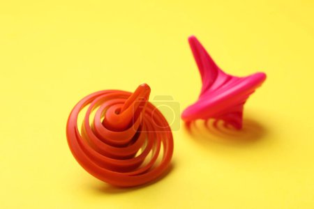 Red and pink spinning tops on yellow background, closeup
