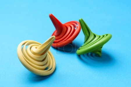 Photo for Many colorful spinning tops on light blue background, closeup - Royalty Free Image