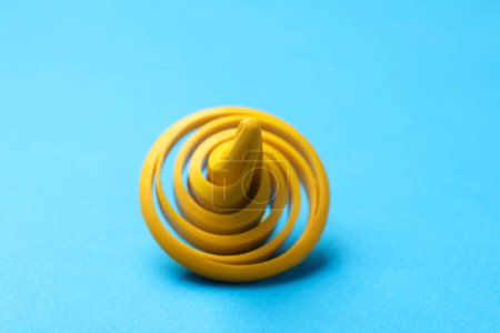 One yellow spinning top on light blue background, closeup