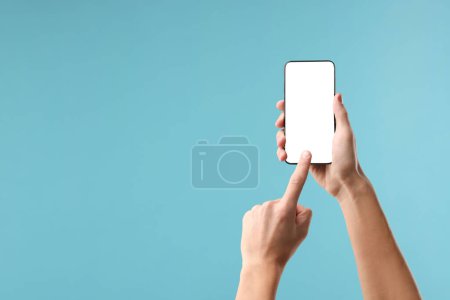 Mann mit Smartphone mit leerem Bildschirm auf hellblauem Hintergrund, Nahaufnahme. Mockup für Design